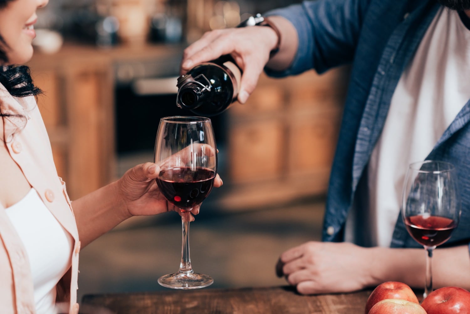 man pouring red wine for woman