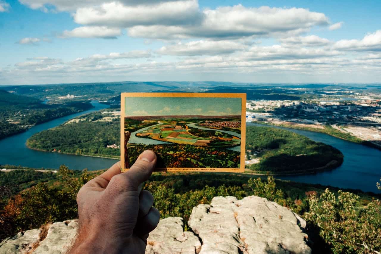 pexels-kelly-2928248 person holds old picture of the tennessee river bend in front of the current view