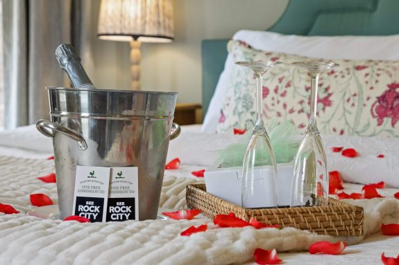 rose pedals on bed with champagne glasses and two Rock City tickets