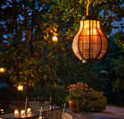 The back patio of the Chanticleer Inn shows candlelit tables in a dense garden at dusk.